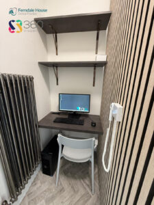 A modern dental X-ray machine from Acteon, labeled "X-Mind Optima," mounted on a wall in a dental practice. The machine features a curved arm with a control panel and a headrest, set against a wooden slatted wall and a light-colored room with a tiled floor. The logo and name "Ferndale House Dental Practice" are visible, along with a "360 Visualise" watermark.